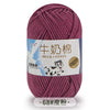 A skein of purple milk cotton blend yarn with a label indicating stretch properties.