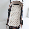 A beige and brown stroller cushion with a pattern of small brown bear hearts.