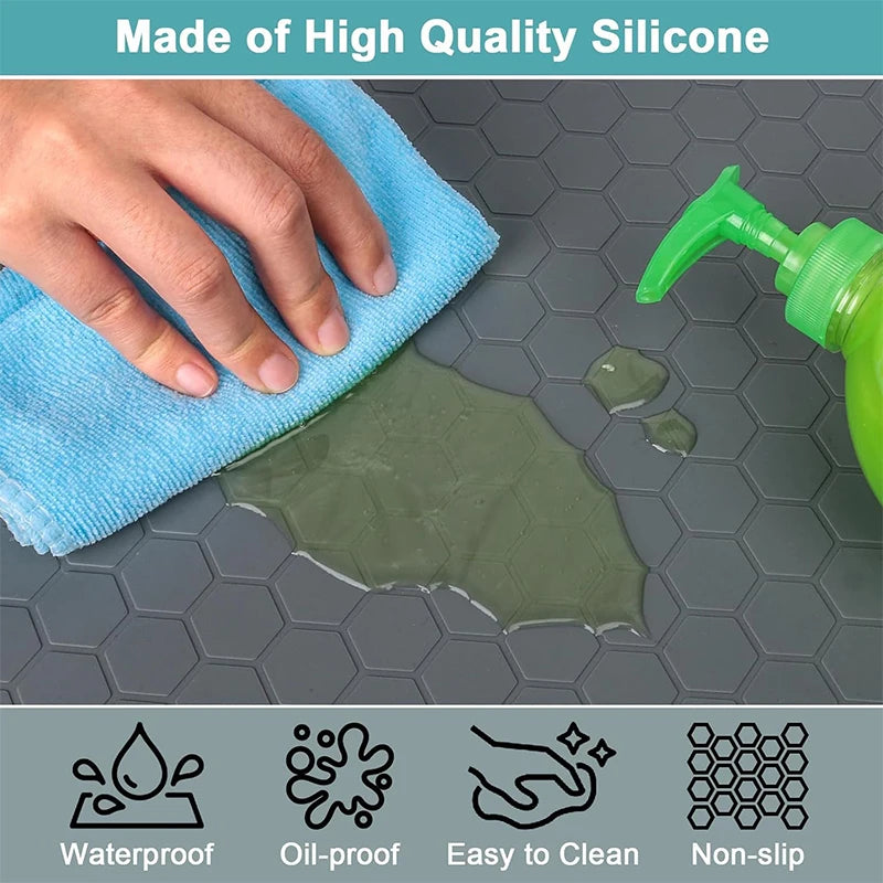 A hand is cleaning a green silicone mat on a gray surface, demonstrating waterproof, oil-proof, easy-to-clean, and non-slip f