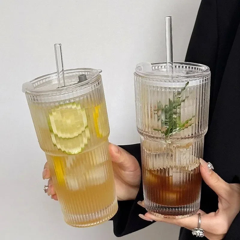 Un verre haut rempli d'une boisson jaune, garni de tranches de lime et d'une feuille verte.