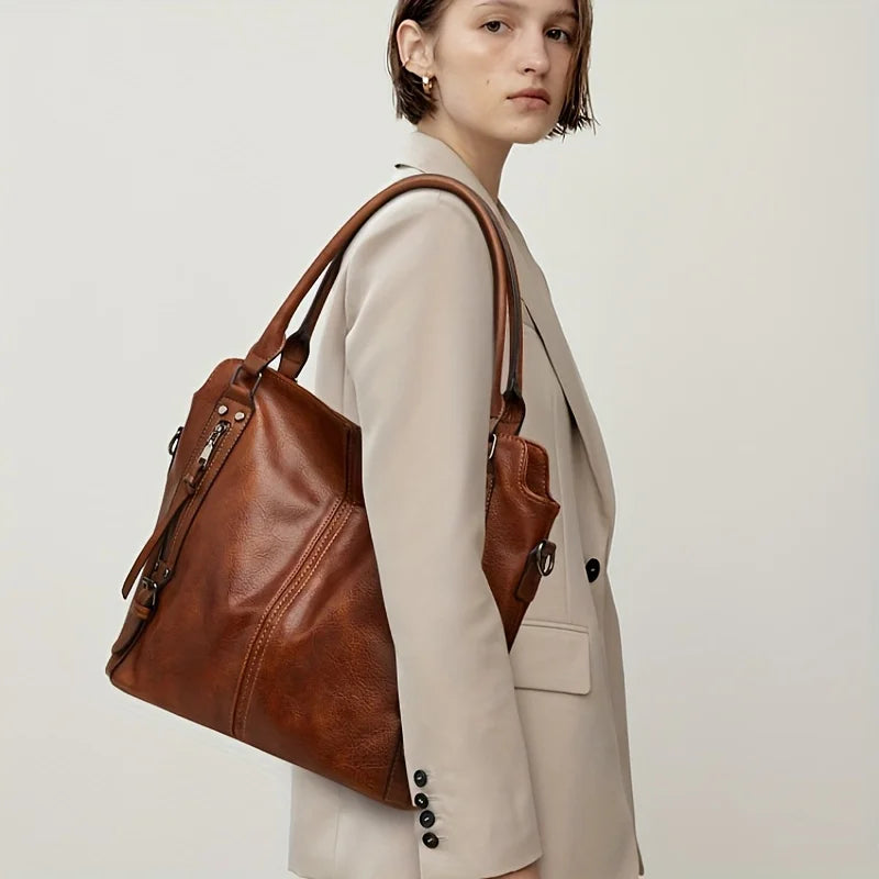 A woman models a tan PU leather tote bag with a detachable strap and a beige blazer.