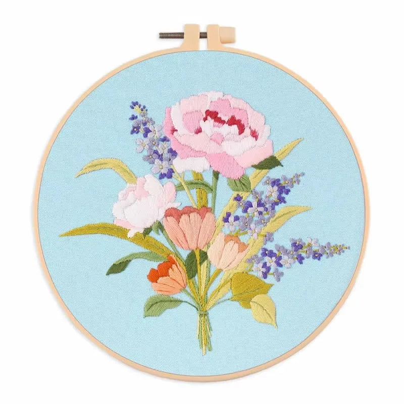 A circular embroidery hoop featuring a pink and purple floral design on light blue fabric.