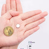 A hand holds a round gold coin magnet next to a measuring scale showing its dimensions.