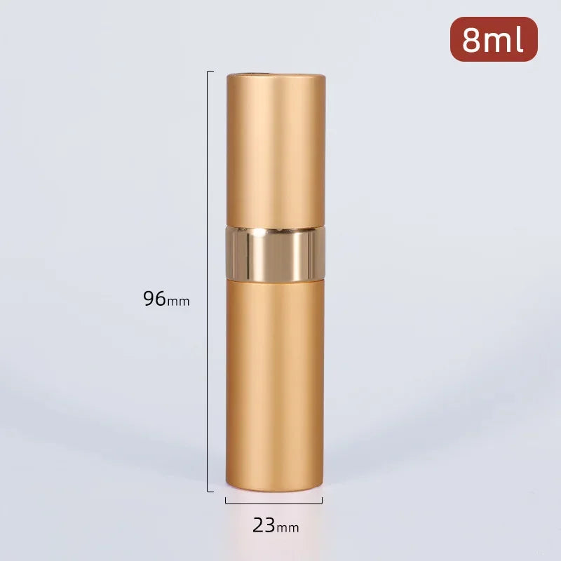 A tall, cylindrical gold-colored perfume atomizer bottle with a silver band and a black cap, shown against a light gray backg
