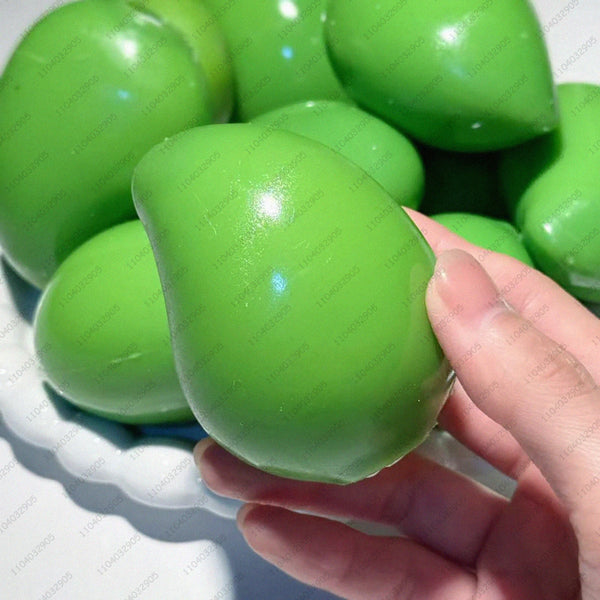 Eine Hand hält einen leuchtend limettengrünen, farbwechselnden Mango-Stressball vor weißem Hintergrund.