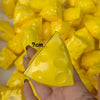 A hand holds a yellow, triangular fidget cube with dimples against a background of similar yellow pieces.
