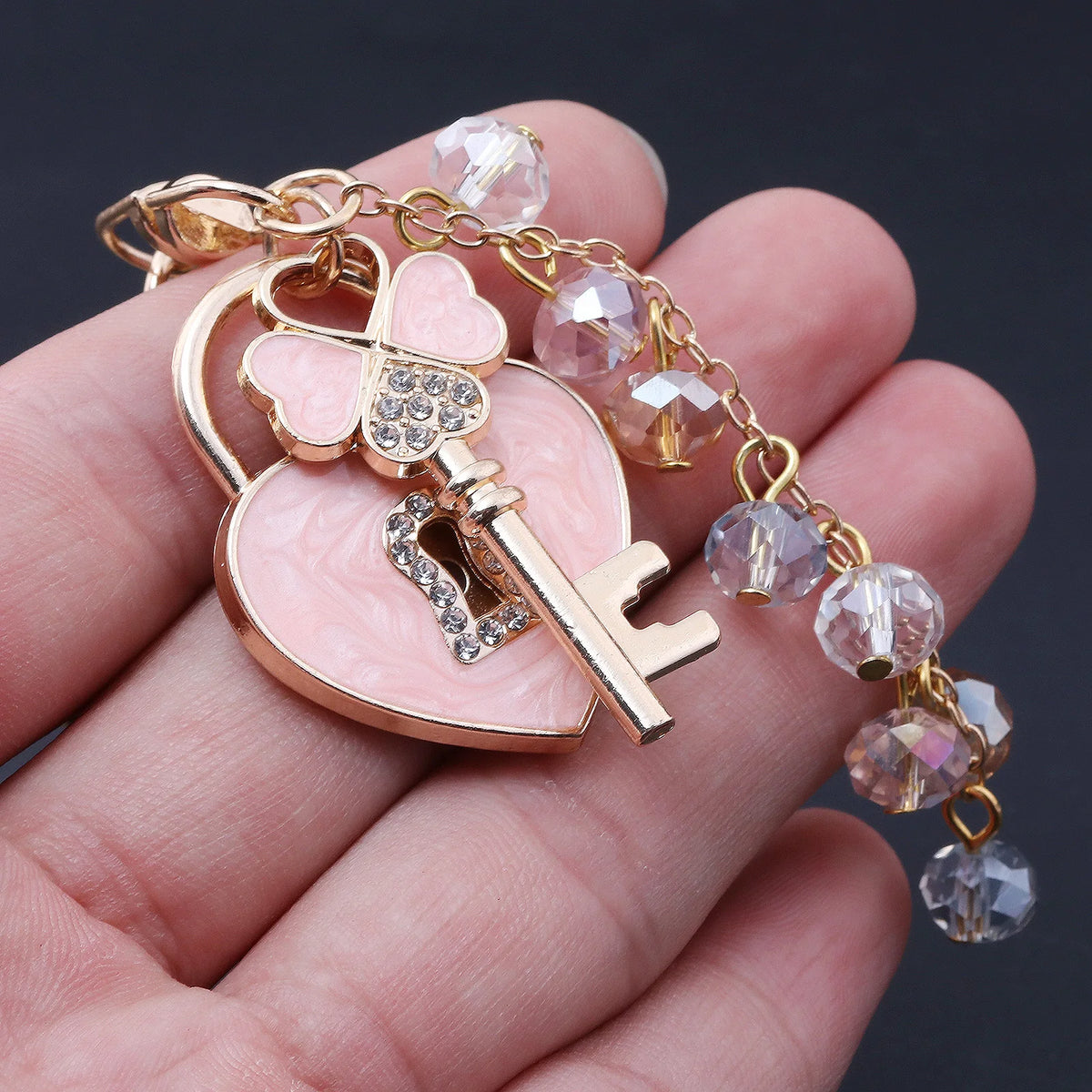 Gold-toned charm featuring a heart and key design with clear rhinestones on a bracelet.