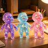 Three squishy stress relief toys in purple, blue, and pink shimmer finish standing on a wooden surface.