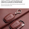 A brown genuine leather car key case cover is shown resting on a dark red fabric surface.