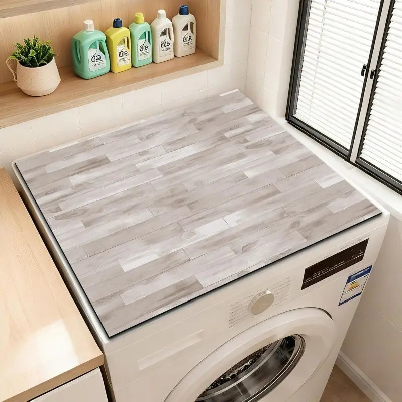 A close-up view of a wood grain waterproof washer and dryer mat placed inside a white washing machine.