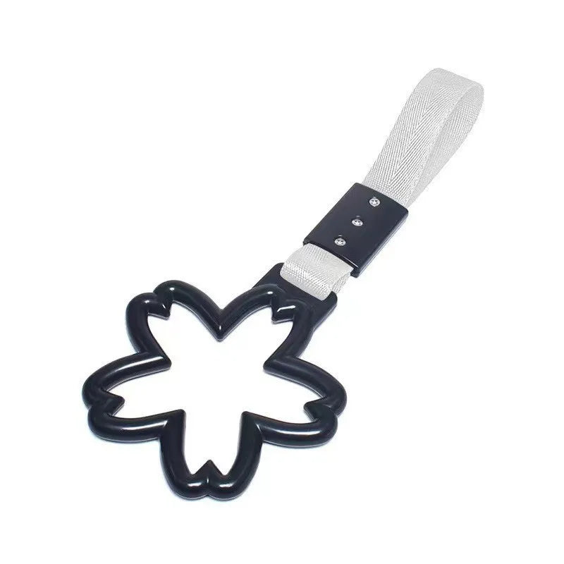 A black steel hook attached to a white strap with a gray fabric loop.