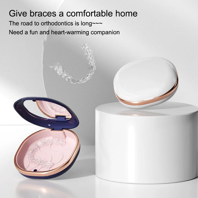 A compact orthodontic retainer case with a built-in mirror is shown open on a white stand.