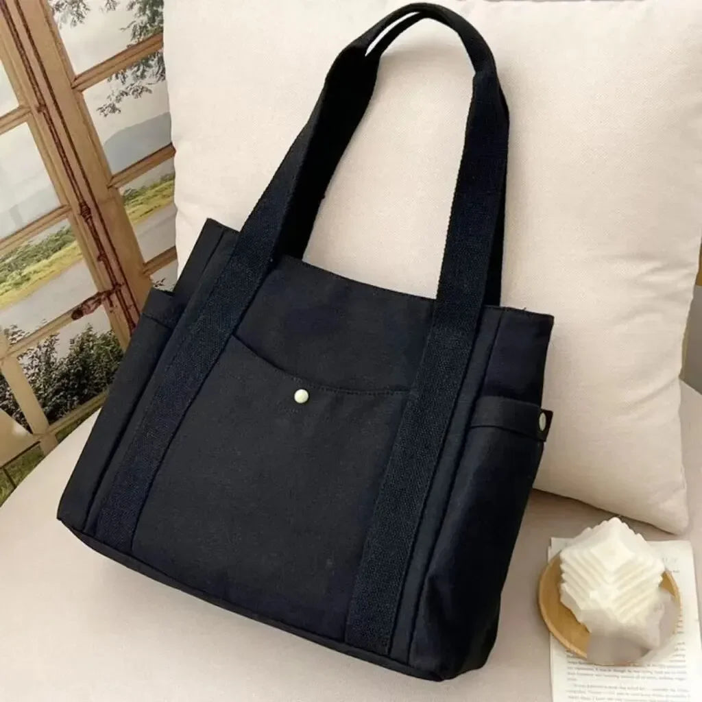 Una bolsa de tela negra se muestra en un cojín blanco junto a un marco de madera.