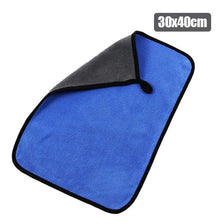 A blue microfiber car drying towel with a black grip and a gray top section.