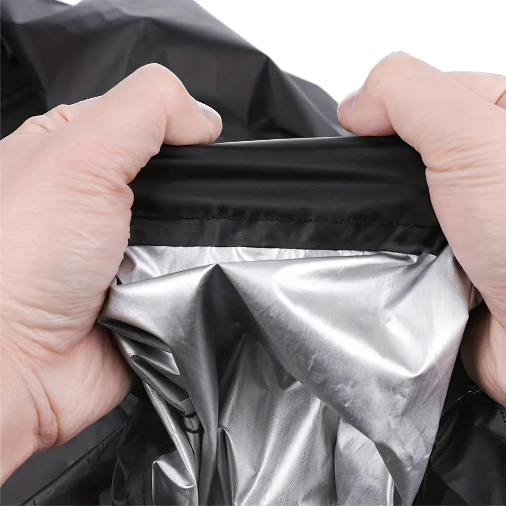 Hands are opening a black heavy-duty outdoor push mower cover to reveal a shiny silver protective layer.
