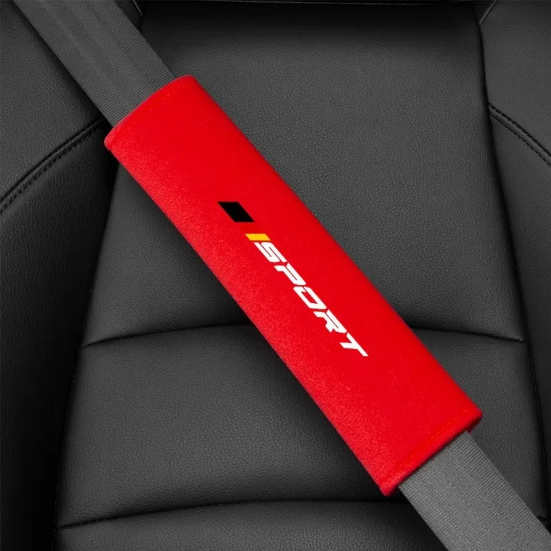 A red and black car seat belt cushion is shown against a dark gray car seat fabric.