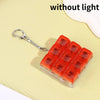 An orange LED mechanical keychain fidget toy with custom keycaps resting on a light yellow surface.