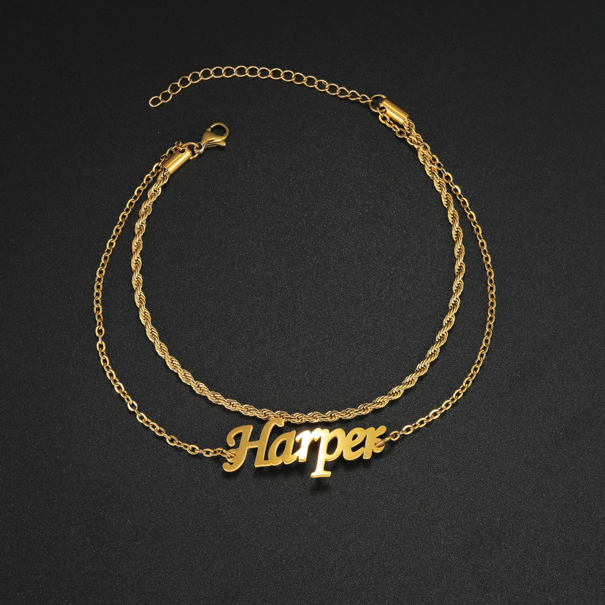 Gold double-layer chain necklace with the name Harper engraved on a black background.