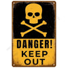 A vintage metal tin sign with a black background featuring a yellow skull and crossbones symbol and the text DANGER KEEP OUT.