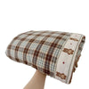 A plaid muslin baby blanket with floral embroidery and a beige trim is shown folded.