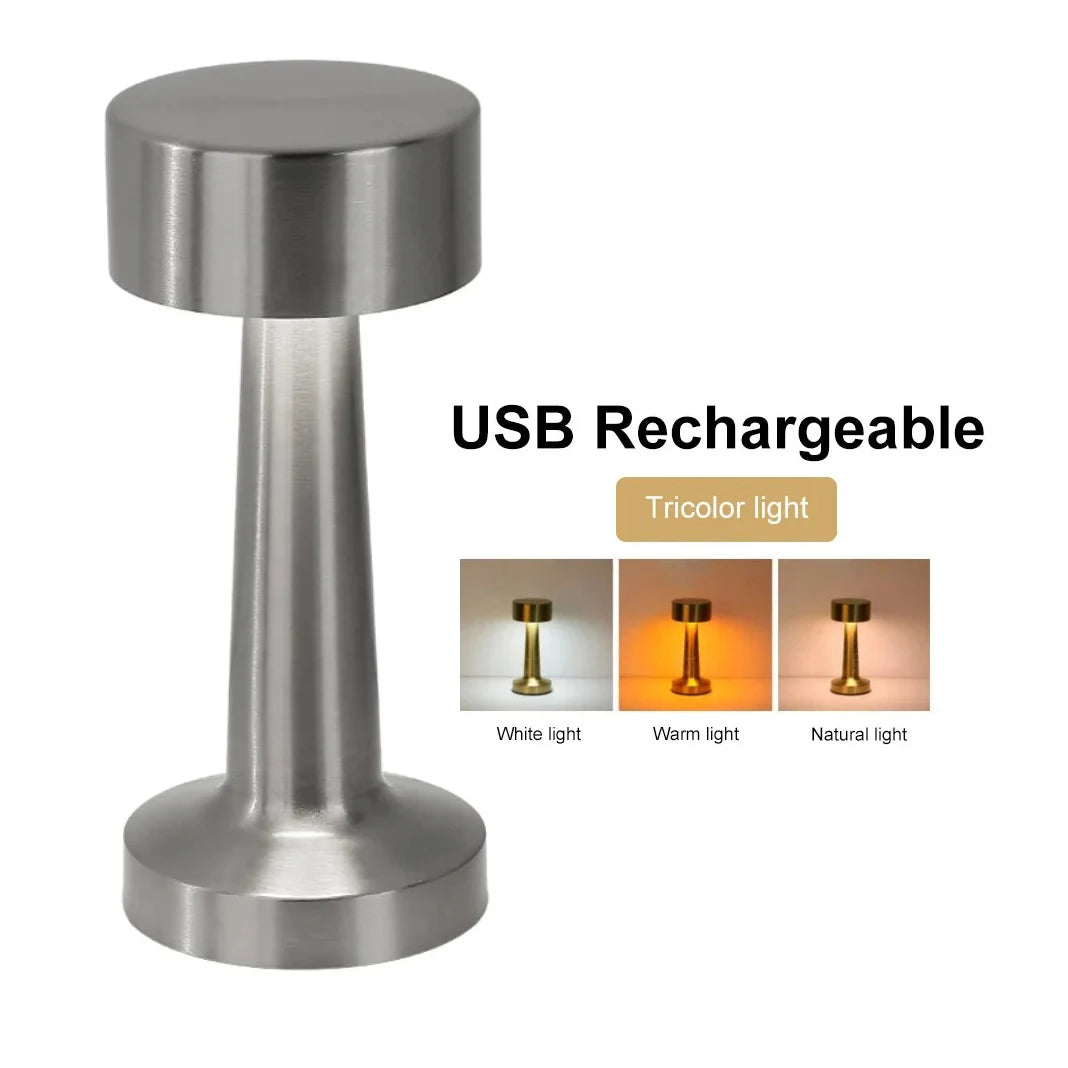 A silver metal rechargeable USB LED table lamp with a cylindrical base and adjustable light color options.