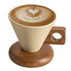 A latte art coffee in a ceramic cup resting on a wooden base with a spoon.
