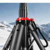 A black tripod with a red grip and a blue light is set up in the snow, ready for smartphone vlogging.