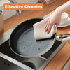 A hand wipes a non-stick frying pan with a waffle weave towel in a kitchen setting.