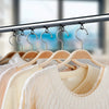 A display of cream and beige knitted sweaters hanging from a metal rack with silicone hooks.