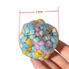 A hand holds a colorful, squishy sensory stress ball with various pastel-colored, bubbly textures.