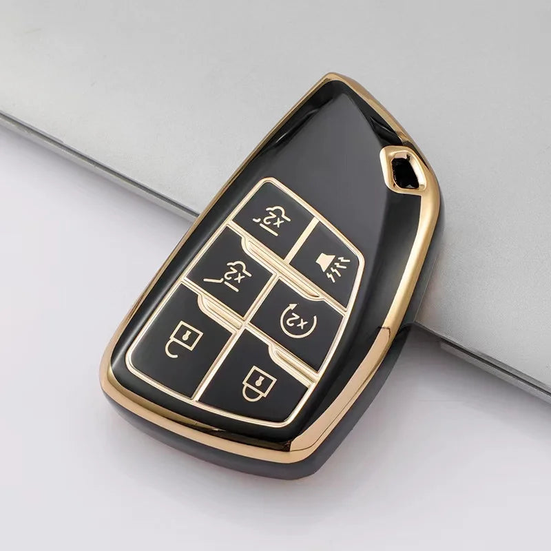 A black and gold durable TPU car key fob cover with various buttons shown on a gray background.
