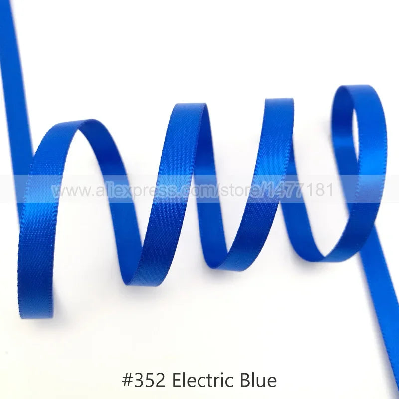 A blue satin ribbon is shown coiled and unwound against a white background.