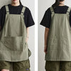 A person wearing a khaki green waterproof work apron over a black shirt and olive pants.