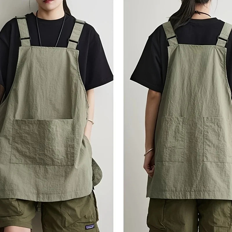 A person wearing a khaki green waterproof work apron over a black shirt and olive pants.