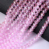 Pink faceted crystal glass spacer beads arranged in strands on a dark surface.