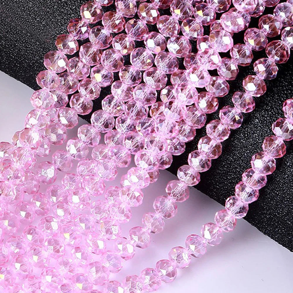 Pink faceted crystal glass spacer beads arranged in strands on a dark surface.