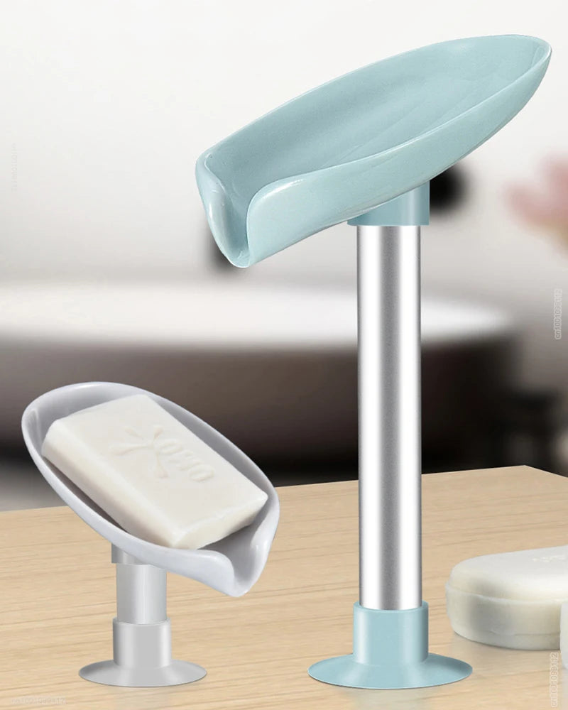 A silver soap dish with a light blue leaf-shaped suction cup holder and a white bar of soap.