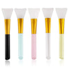 A set of five silicone facial mask brushes with white heads and gold bases in various pastel colors.