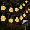 String lights with yellow crystal-like bulbs are strung outdoors in the dark rain.