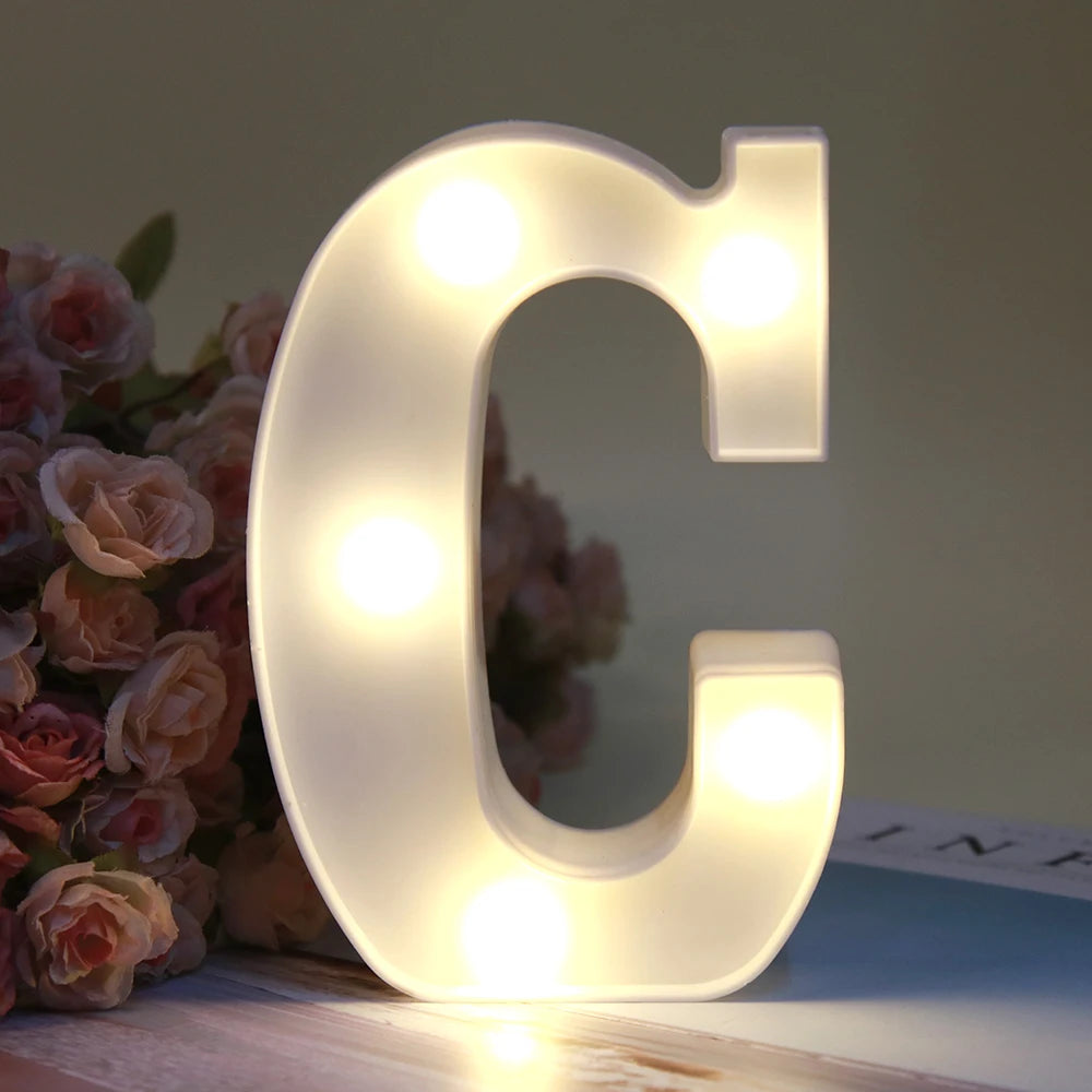Lumière de nuit en forme de lettre C, alphabet blanc lumineux LED sur une surface en bois.