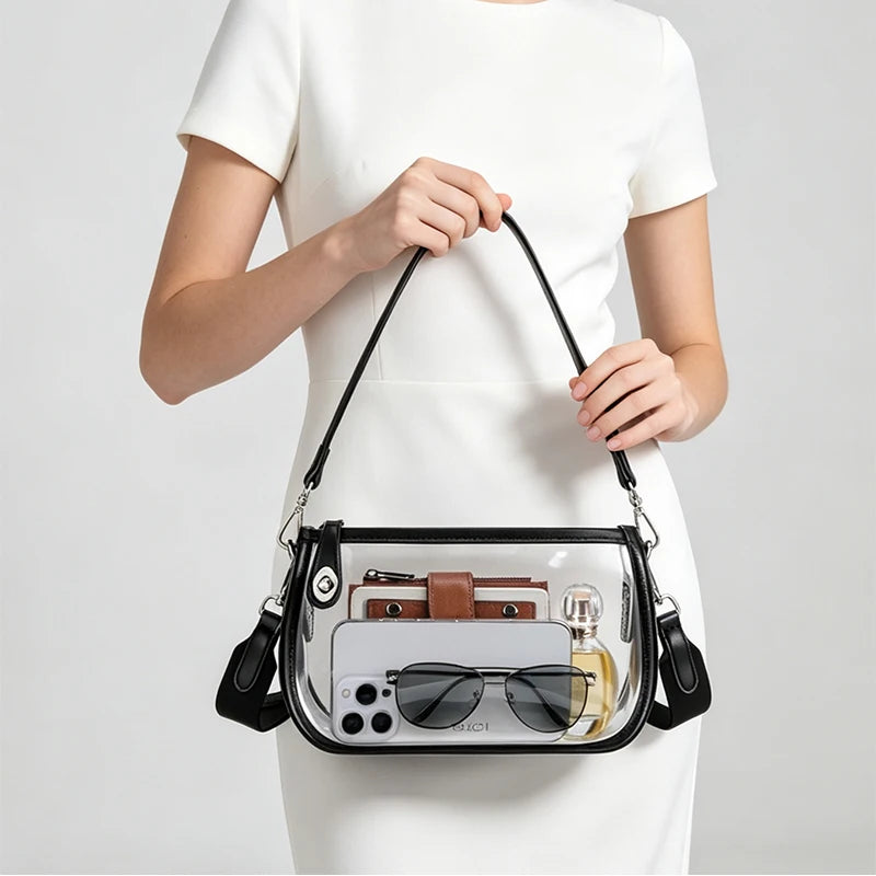 A clear PVC shoulder bag with a black adjustable strap is held by a woman against a white background.