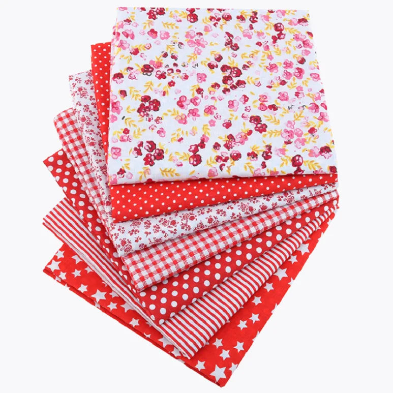 A bundle of red, white, and pink cotton fabric squares featuring various floral, dot, and plaid patterns for patchwork.