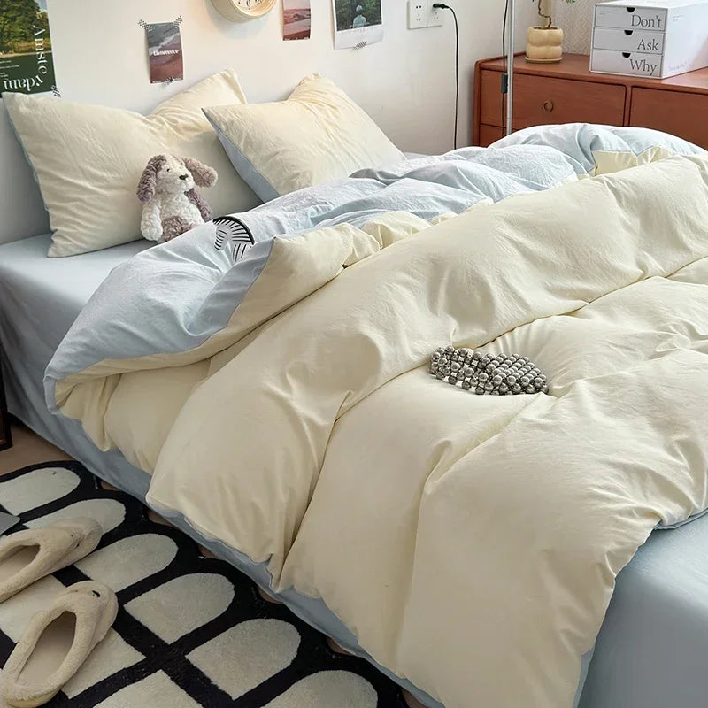 A beige duvet cover set with a light blue accent and white pillows is displayed on a bed.