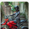 A person wearing a black helmet and leather gloves sits on a red Ducati motorcycle with a black hip pack attached.