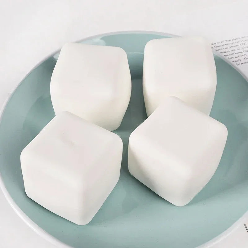 White squishy milk tofu fidget toys resting on a light blue ceramic plate.