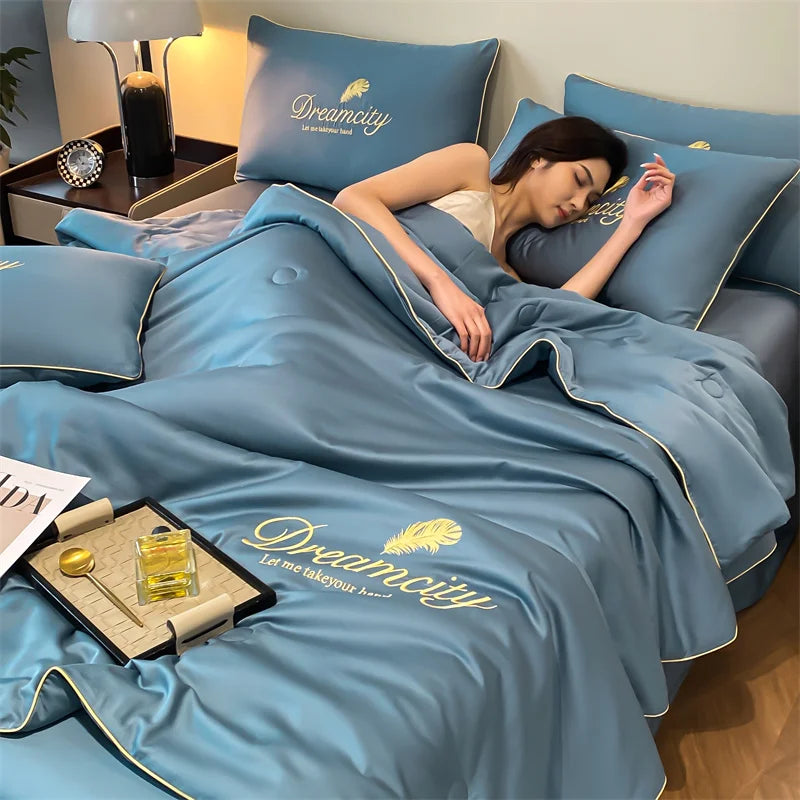 A woman is relaxing on a blue comforter featuring the Dreamcity embroidery on a bed.