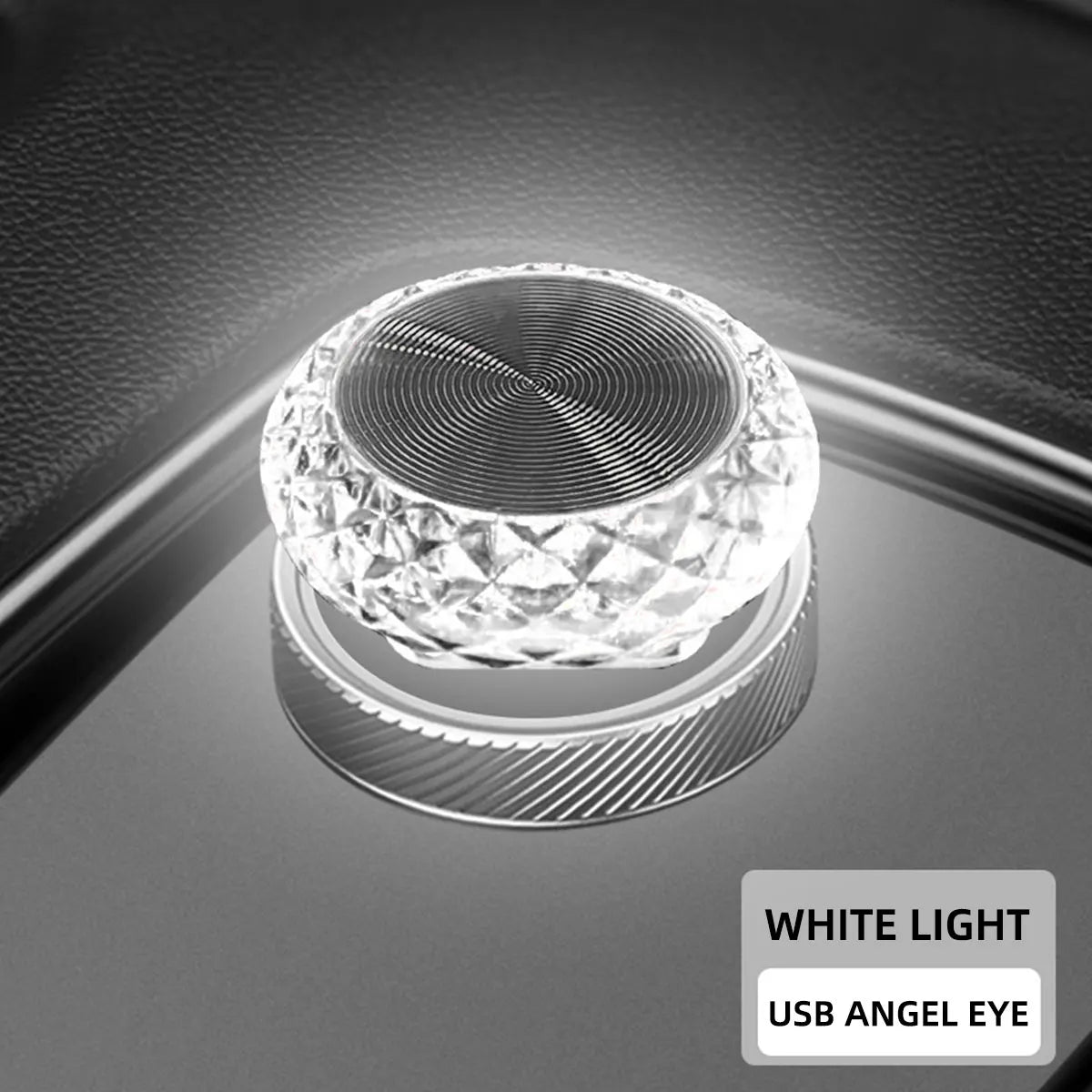 A close-up of a clear crystal LED light fixture with a USB angel eye design resting on a dark surface.