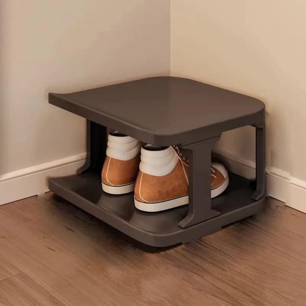 A dark gray stackable vertical shoe rack holding pairs of brown and tan boots on a wooden floor.