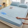 A light blue floral waterproof fitted mattress protector is displayed on a bed, with a hand touching the fabric.