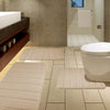 A set of beige plush memory foam bath mats with non-slip backing placed on a tiled bathroom floor.